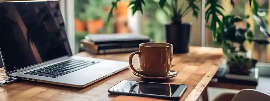 Foldable smartphone in multitasking mode on a desk with a laptop and coffee mug.