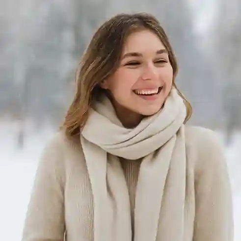 Person wearing a cashmere sweater and scarf outdoors in the snow, showcasing warmth and luxury as one of the best fabrics for cold weather